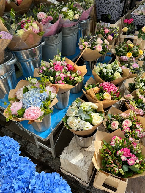 A display of freshly arranged floral bouquets and arrangements at Kennington Flowers, featuring a variety of pastel-colored roses, hydrangeas, and carnations wrapped in brown kraft paper and placed in